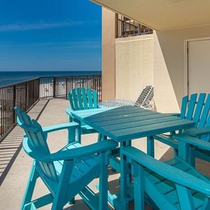 Relax on the turquoise patio furniture while enjoying the beautiful beach view from this inviting balcony