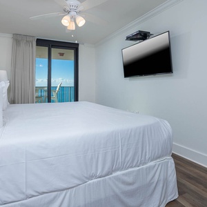 Inviting master suite with a comfortable king bed, a TV, and access to a balcony showcasing beautiful views