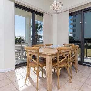 Dining area features a rustic wood table surrounded by six chairs, with sliding glass doors leading to a balcony view
