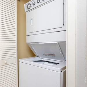 A stacked washer and dryer set is neatly tucked away in a closet, offering convenient laundry options for guests