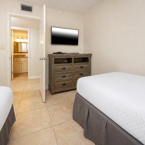 This cozy bedroom features two twin beds, a flat-screen TV, and an adjoining bathroom for your convenience