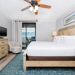 Relax in this inviting master bedroom featuring a king bed, a cozy chair, and a TV, with easy access to the beach balcony