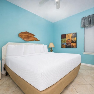Brightly colored walls complement the inviting king bed, while a tasteful artwork and TV enhance the room's charm