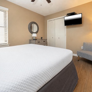 Comfortable guest bedroom featuring a queen bed, a cozy chair, and a flat-screen TV