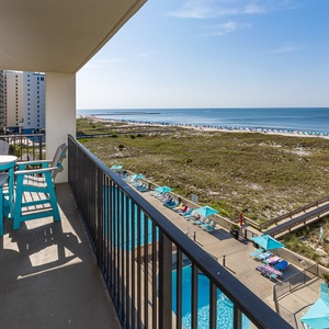Turquoise chairs surround the balcony table where you hear distant laughter and poolside splashes below
