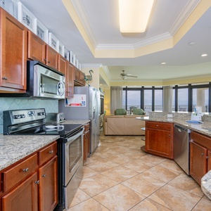 Modern kitchen with granite countertops, stainless appliances, and a bright view of the inviting living area and balcony