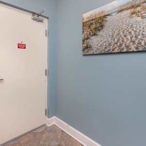 Step into a welcoming entryway featuring a beach-themed artwork and a secure door for your peace of mind