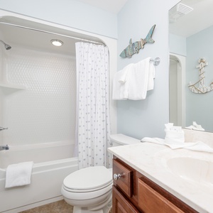 Guest bathroom featuring a tub/shower combo, stylish decor, and fresh towels for a relaxing stay
