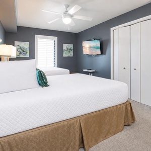 Relax in the guest bedroom featuring two double beds, a TV, and coastal decor for a restful getaway