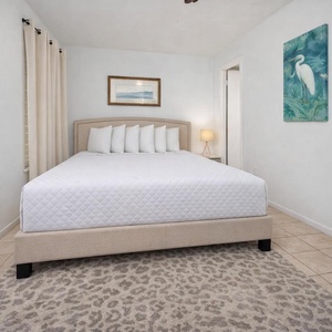 This bedroom features a plush bed, soft rug, and calming artwork, perfect for a restful getaway