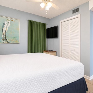 Relax in the serene king suite featuring a plush bed, a TV, and calming decor highlighted by soft green curtains