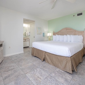 Brightly decorated master bedroom featuring a king bed, large TV, and an en-suite bathroom with modern fixtures