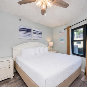 Calm queen suite with a cozy bed welcomes you to rest beneath the ceiling fan after a day exploring