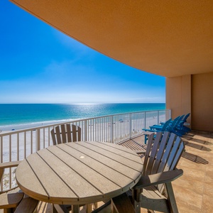 Savor your morning coffee at the round table, surrounded by vibrant blue chairs and breathtaking beach views