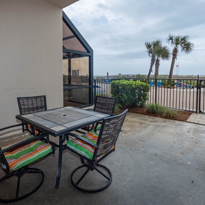 Dine al fresco at the colorful table with comfortable chairs, enjoying views of the nearby pool and palm trees
