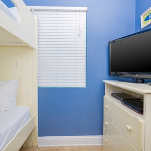 This cozy bedroom features a bunk bed, a TV for entertainment, and cheerful blue walls, perfect for a fun getaway