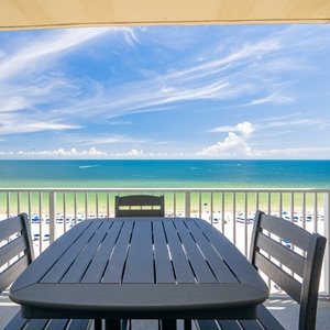 Enjoy breathtaking beachfront views from this balcony with a spacious dining table, perfect for relaxing meals outdoors