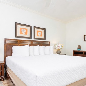 This bedroom features a comfortable king bed with white linens, stylish lamps, and decorative artwork for a relaxing stay