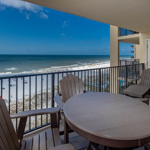 Enjoy the serene beachfront view from the private balcony, featuring a round table and comfortable seating for relaxation