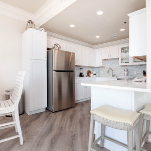 Bright and airy kitchen area features white cabinetry, a breakfast bar with seating, and modern stainless appliances