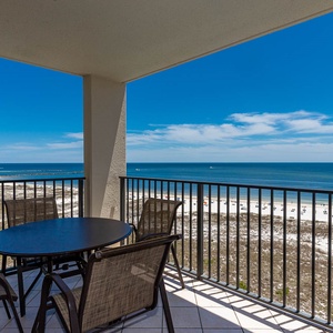 Balcony with a round table and chairs offers a panoramic view of the beach and the tranquil gulf waters beyond
