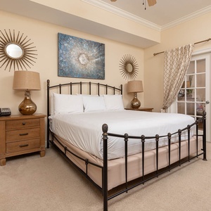 The master bedroom features a stylish king bed, elegant decor, and access to the dining area through French doors