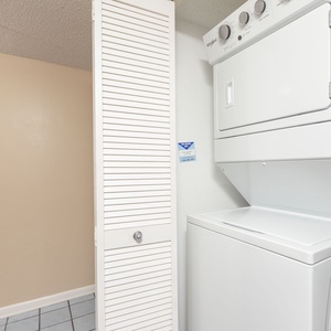 Compact laundry area features a stacked washer and dryer, complemented by a white louvered door for added privacy
