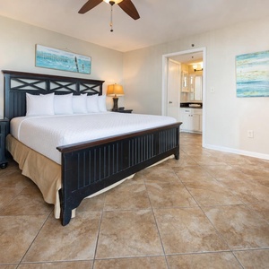 The master bedroom features a stylish dark wood king bed, warm tile flooring, and a cozy ambiance, perfect for relaxation