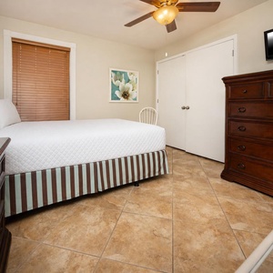 This cozy guest bedroom features a queen bed, a flat-screen TV, and warm wood accents, perfect for a restful getaway