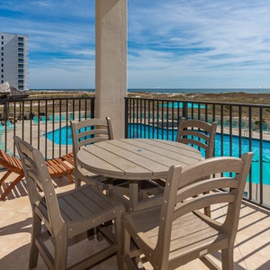 Balcony seating offers a view of the pool area and the beach beyond, perfect for relaxing in the sun