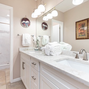 Refresh after a day at the beach in the master bath featuring an elegant vanity and tile walk-in shower