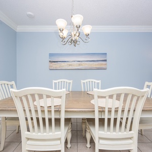 Gather around the rustic dining table, surrounded by light blue walls and coastal artwork, for memorable meals