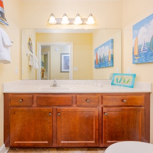 Additional half bath featuring a vanity, colorful sailboat artwork, and plush towels for a refreshing stay