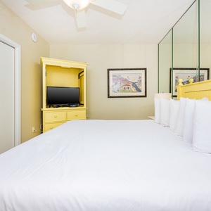 Rest in the inviting bedroom featuring a king bed, a TV, and cheerful yellow accents that brighten your stay