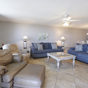 Living area features comfortable blue sofas, a light-colored coffee table, and decorative lamps for a relaxed atmosphere