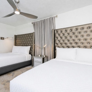 Relax in this stylish bedroom featuring two plush queen beds with elegant tufted headboards and modern bedside lighting