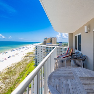 Enjoy breathtaking beachfront views from this balcony, featuring comfortable seating and a round wooden table