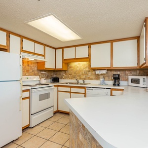Bright kitchen features white cabinetry, a spacious countertop, and a cozy breakfast bar perfect for casual dining