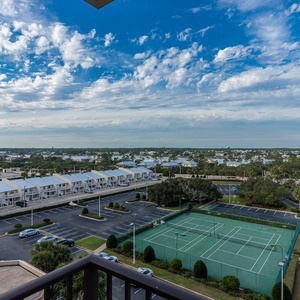 Enjoy the expansive view from your balcony, overlooking tennis courts and lush greenery in a vibrant setting