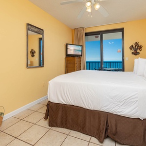 Sleep soundly in this master suite bedroom featuring a king bed and a view of the beach through sliding glass doors