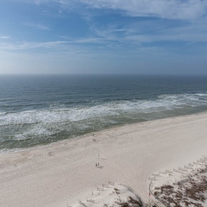 Enjoy the tranquil view of gentle waves and a wide stretch of shoreline, perfect for relaxation and beach walks