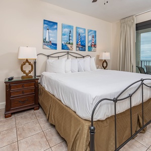 Relax in this master bedroom featuring a comfortable king bed, decorative artwork, and beachfront balcony access