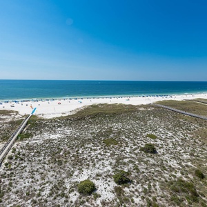 Stunning view of the beach and turquoise gulf waters, dotted with colorful umbrellas and beachgoers