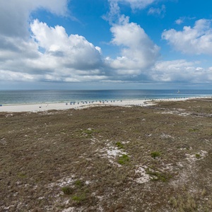 Relaxing view of the beach with white sand, dotted with umbrellas, and a glimpse of the pool area nearby under a bright sky