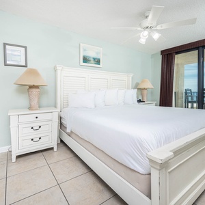 Unwind in the master bedroom featuring a king bed, stylish decor, and a view of the beachfront balcony