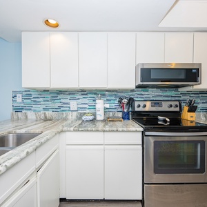 This kitchen features a spacious design, a beautiful granite countertop, and a stylish blue mosaic backsplash