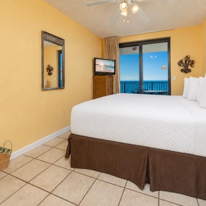 Sleep soundly in this master suite bedroom featuring a king bed and a view of the beach through sliding glass doors