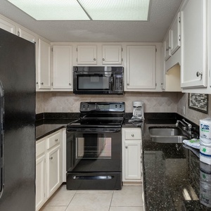 This kitchen features sleek black appliances, granite countertops, and a convenient coffee maker for your morning brew