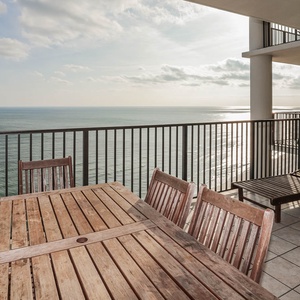 This inviting balcony features a wooden dining table and lounge chair, enjoy beach views from the twenty-fourth floor