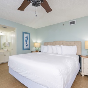 Spacious master bedroom featuring a comfortable king bed, coastal decor, and an en-suite bathroom